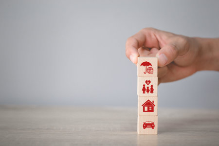 Hand arranging wood block stacking with icon insurance: car,
 real estate and property, travel,...