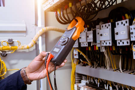 Electrician measurements with multimeter testing current electric in control panel.の写真素材