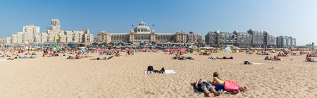 SCHEVENINGEN, THE HAGUE, NETHERLANDS - JULY 3, 2015: People sunbathing on Scheveningen beach and skyline with Kurhaus in the city of The Hague, Netherlandsのeditorial素材