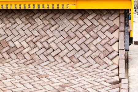Brick road making machine laying out a carpet of bricks in formation to create new paving on road or street, Netherlandsの写真素材