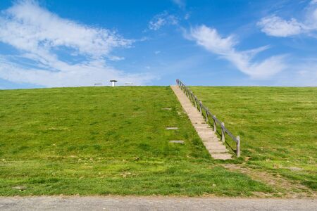 Stairway to top of dyke with picnic table. Dyke protects Friesland polder from  Waddensea,...