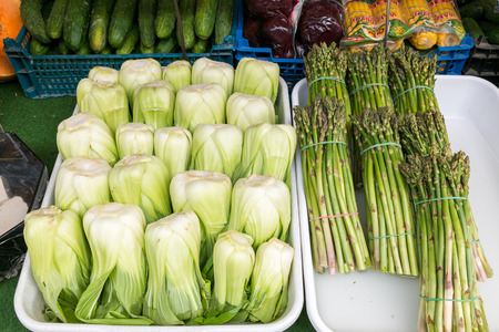 Chinese cabbage bok choy and bundles of fresh asparagus displayed in market stand on Naschmarkt in Vienna, Austriaのeditorial素材