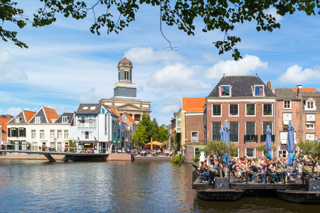 Hartebrugkerk church tower and people on outdoor terrace of cafe on Rhine canal in Leiden, South Holland, Netherlandsのeditorial素材