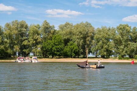 WOUDRICHEM, NETHERLANDS - JUN 4, 2017: Motorboats and traditional sailboat sailing on river Afgedamde Maas near fortified town of Woudrichem, North Brabant, Netherlandsのeditorial素材
