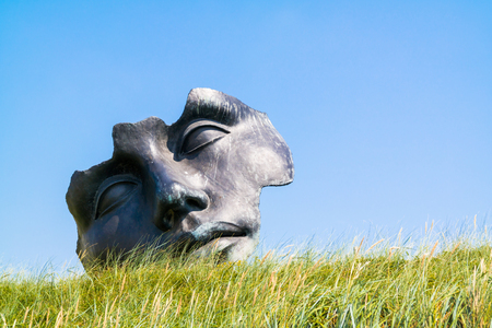 SCHEVENINGEN, NETHERLANDS - JUL 3, 2015: Light of the moon sculpture by Igor Mitoraj in dunes, public art of Museum Sculptures by the sea in Scheveningen, The Hague, South Holland, Netherlandsのeditorial素材