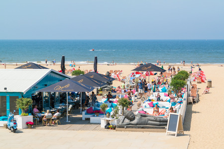 People enjoying and relaxing on lounge terrace of waterfront beach club in Scheveningen, The Hague, Netherlandsのeditorial素材