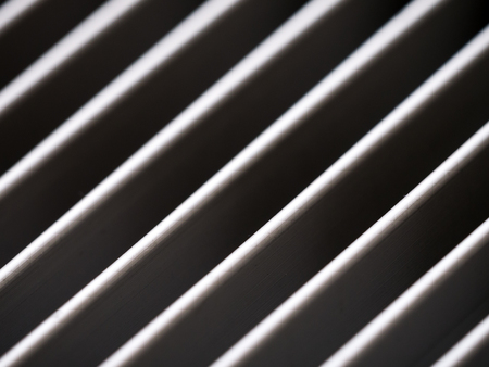 Close-up of aluminum cover grille with pattern of diagonal lines in shadow and light, black and whiteの写真素材