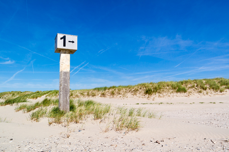 Marked beach pole with number 1 in sand on dune with marram grass on Kennemerstrand beach in IJmuiden, Noord-Holland, Netherlandsの写真素材