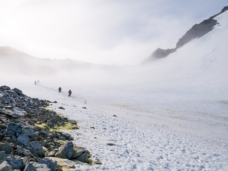 People hiking up and down snow slope of Spigot Peak in mist, Graham Land, Antarctic Peninsula,...