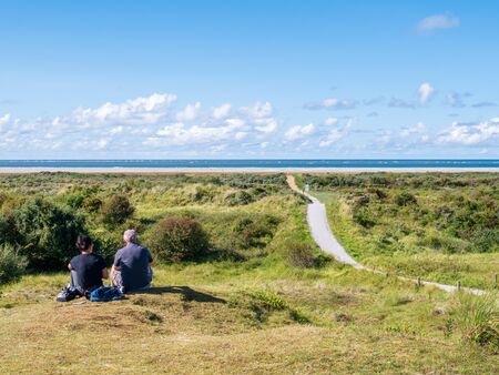 People relaxing in dunes and footpath to North Sea beach on Frisian island Schiermonnikoog, Netherlandsのeditorial素材