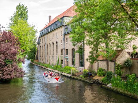 People on boat tour on Bakkersrei canal in old town of Bruges, Belgiumのeditorial素材