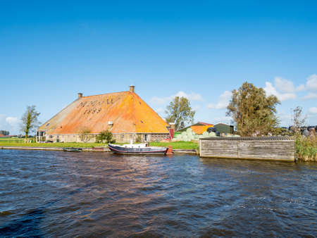 GAASTMEER, NETHERLANDS - OCT 3, 2017: Traditional farmhouse with large roof along Koarte Fliet canal in Gaastmeer, Frieslandのeditorial素材