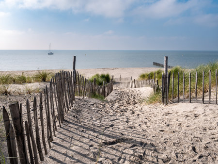 Footpath in sand dunes to beach of Marker Wadden island and sailboat on Markermeer lake, Netherlandsの写真素材