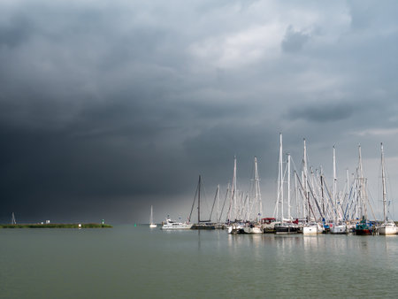Threatening overcast sky with dark storm clouds over sailboats in marina, Enkhuizen, Noord-Holland, Netherlandsのeditorial素材