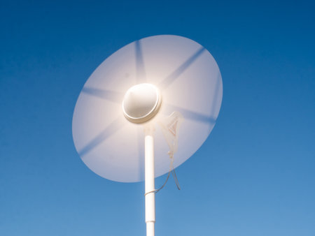 Blades of white wind charger spinning against a blue sky, sustainable energy for boatingの写真素材