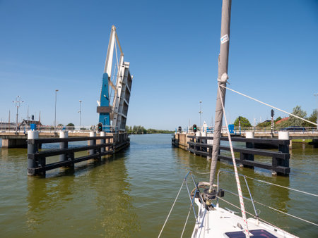 Sailboat approaching bridge waiting for opening - 4/4, Warnsebrug bridge over Johan Frisokanaal channel in Friesland, Netherlandsのeditorial素材