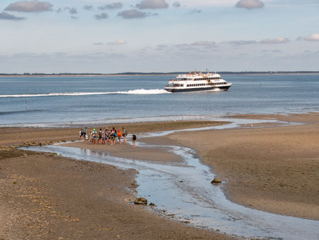 Mudflat hiking at low water and ferry in Wittdun channel, Amrum island, North Frisia, Schleswig-Holstein, Germanyのeditorial素材