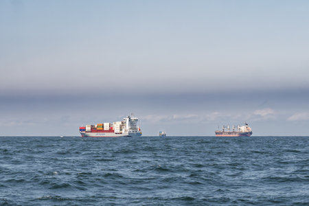 Container feeder ship and bulk carriers at anchor in Jade-Weser estuary anchorage area, German...