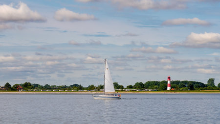 Sailboat sailing in Gelting Bay along coastline near FalshÃ¶ft lighthouse, Pommerby,...