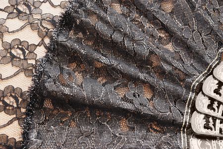 A black fan is exposed and lies on a background a lace                  
