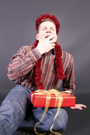 A man yawns, laying  the not opened gift on knees                   の写真素材
