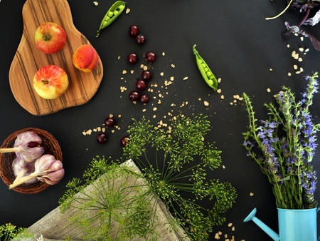 Decorative composition of greenery, fresh yellow flowers, sea salt, spices on a dark background, top viewの写真素材