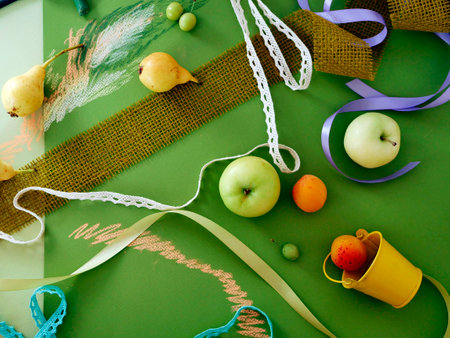 Decorative autumn composition of fruits, decor, greens on green toned paper, painted with pastel, top viewの写真素材