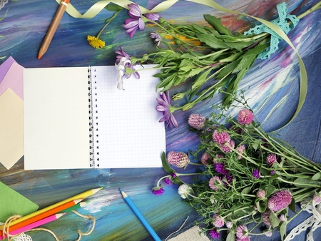 Bright decorative composition of art materials, notepad and flowers on a chalky blue background, the concept of autumn and school, top viewの写真素材