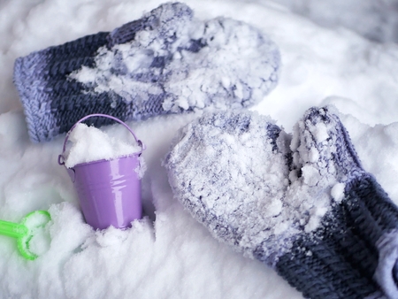 Woolen mittens in the snow, a toy bucketの写真素材