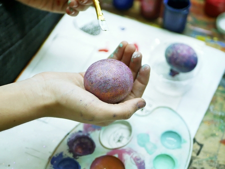 hands of the student painted eggs for easterの写真素材