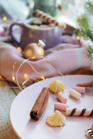 A cup of coffee with meringues and dessert, a warm scarf, Christmas decor, illuminationsの写真素材