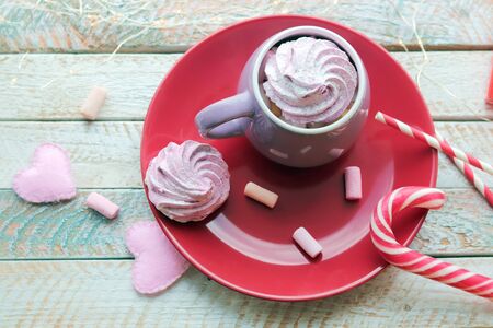 Cup of coffee with meringues and marshmallows, hearts, illumination on a wooden windowsillの写真素材