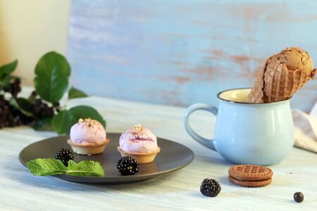 Chocolate ice cream in waffle cones, cookies, berries on a wooden table