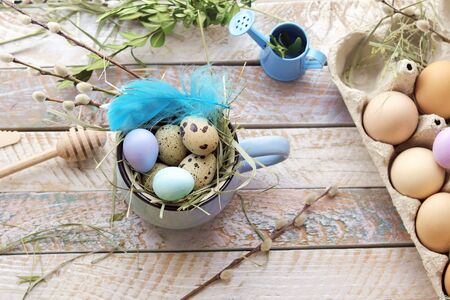 Easter decorative composition, cup, eggs, decor on a wooden surface on a window background