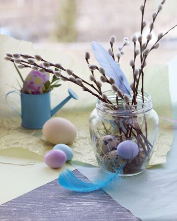 Easter decoration, eggs, pussy-willow branches on a wooden surface on a window background
