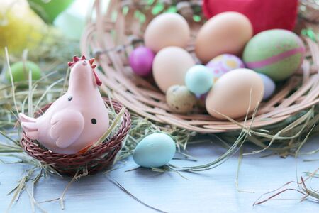 Happy Easter, a basket with painted eggs, a toy chicken, hay on the windowsill