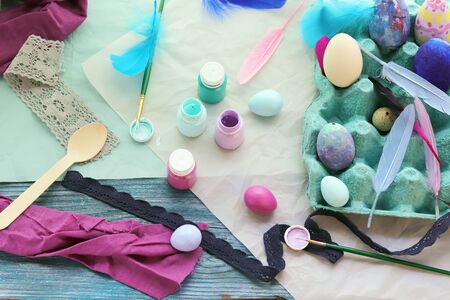 Happy Easter, eggs, paints, brushes, paper on a wooden surface, preparation for the holiday