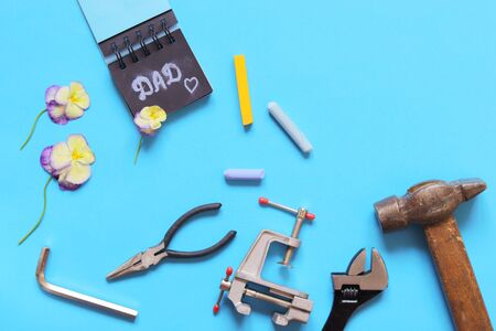 Father's day, tools, inscription dad in a notebook and a heart on a blue background, concept of holiday greetingsの写真素材