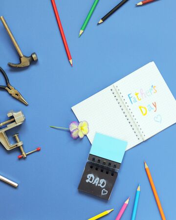 Father's day, tools, inscription dad in a notebook and flower on a blue background, the concept of a holiday congratulationsの写真素材