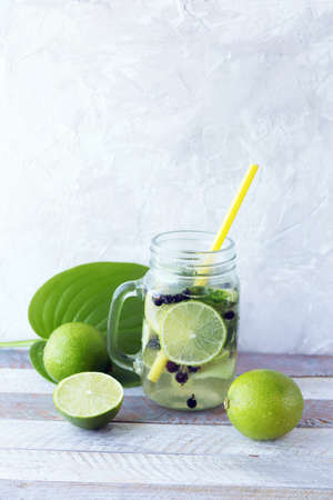 Cold drink of limes, cucumbers and mint in glass cups on a wooden table, detox water, homemade, healthy foodの写真素材