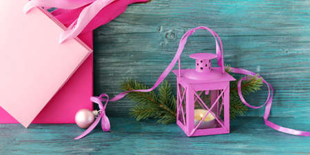 Lantern with a burning candle, fir branches, festive decor, packages for gifts on a woodenの写真素材