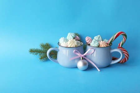 Merry Christmas, two cups of coffee, meringues, spruce branches, festive decor, illumination, blue color background, winter holidays congratulations conceptの写真素材