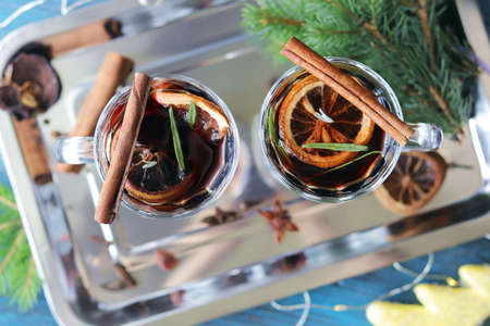 Merry Christmas, cups with mulled wine, spices, New Year's decor, fir branches, illumination on a...