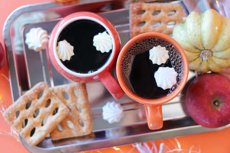 Thanksgiving day, two cups of coffee, meringues, pumpkins, apples, leaves, warm blanket on an orange...