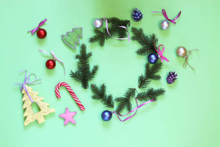 Christmas background, a wreath of fir branches with New Year's decorations on bright green paper, top view, flatlyの写真素材