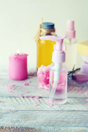 Fresh roses, spray and bottles with aromatic oil on a wooden table, natural home cosmetics, healthy...