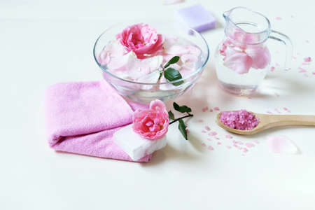 Fresh pink roses, water, petals, candles on a light background, body care products, natural home...