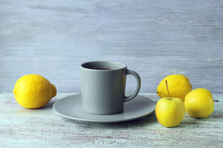 Hot tea in a large cup, lemons and apples on a wooden windowsill, the concept of a vitamin drink for colds, home comfortの写真素材