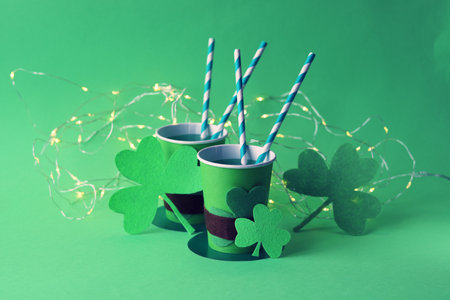 Drink in paper cups in the shape of St. Patrick's hat with straws, shamrock and illumination on...