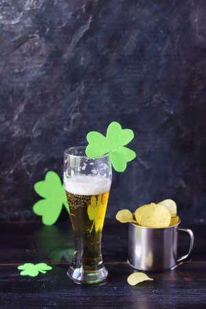 Patrick's day, beer, chips in an iron mug, shamrock on a dark background, party, congratulations, postcardの写真素材